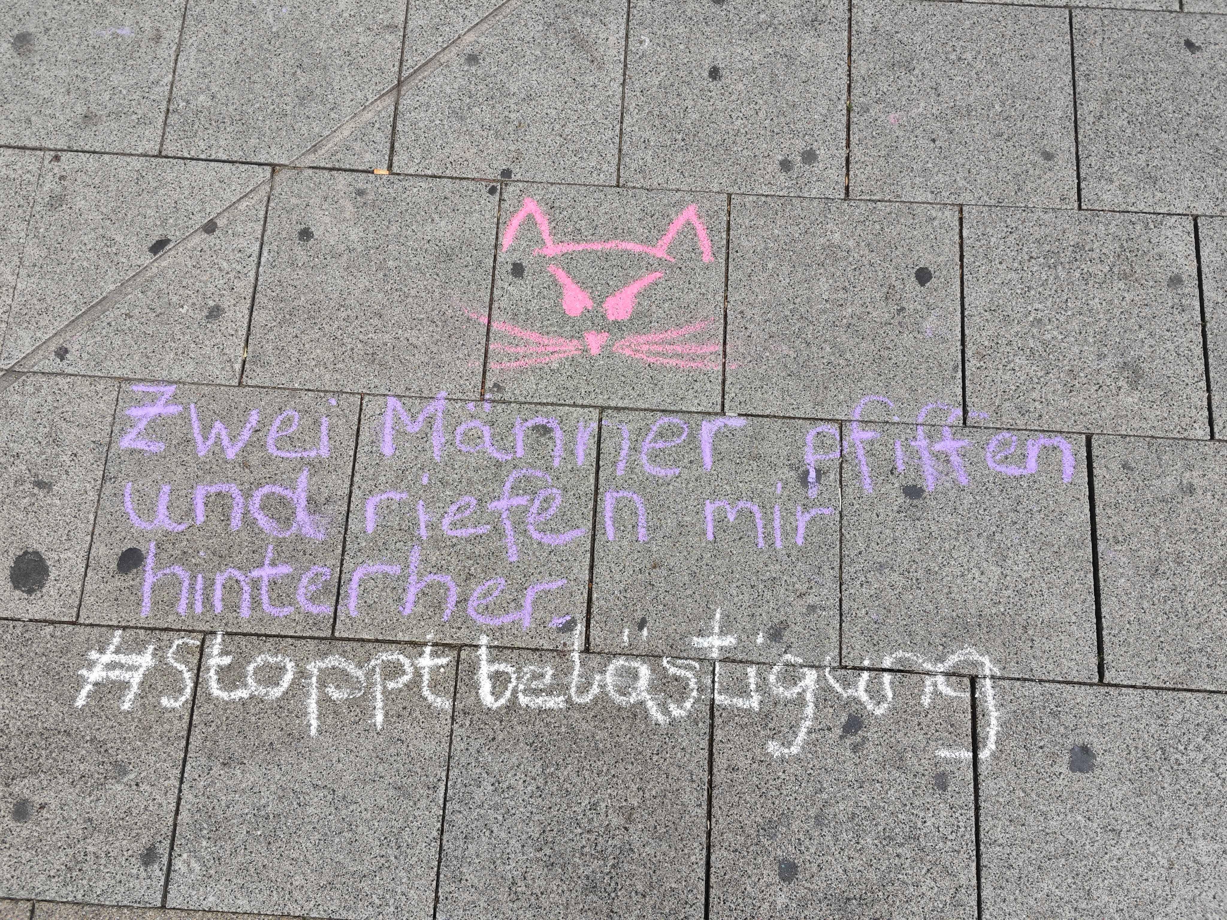 Symbolbild Catcalling: "Zwei Männer pfiffen und riefen mir hinterher - #stoppbelästigung" steht mit Kreide geschrieben in einer Fußgängerzone.