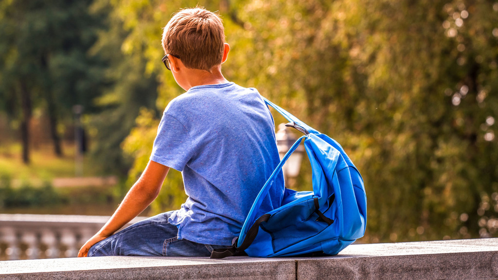 Ein Junge sitzt allein auf einer Mauer. Menschen mit einer Autismus-Spektrum-Störung ziehen sich oft zurück.