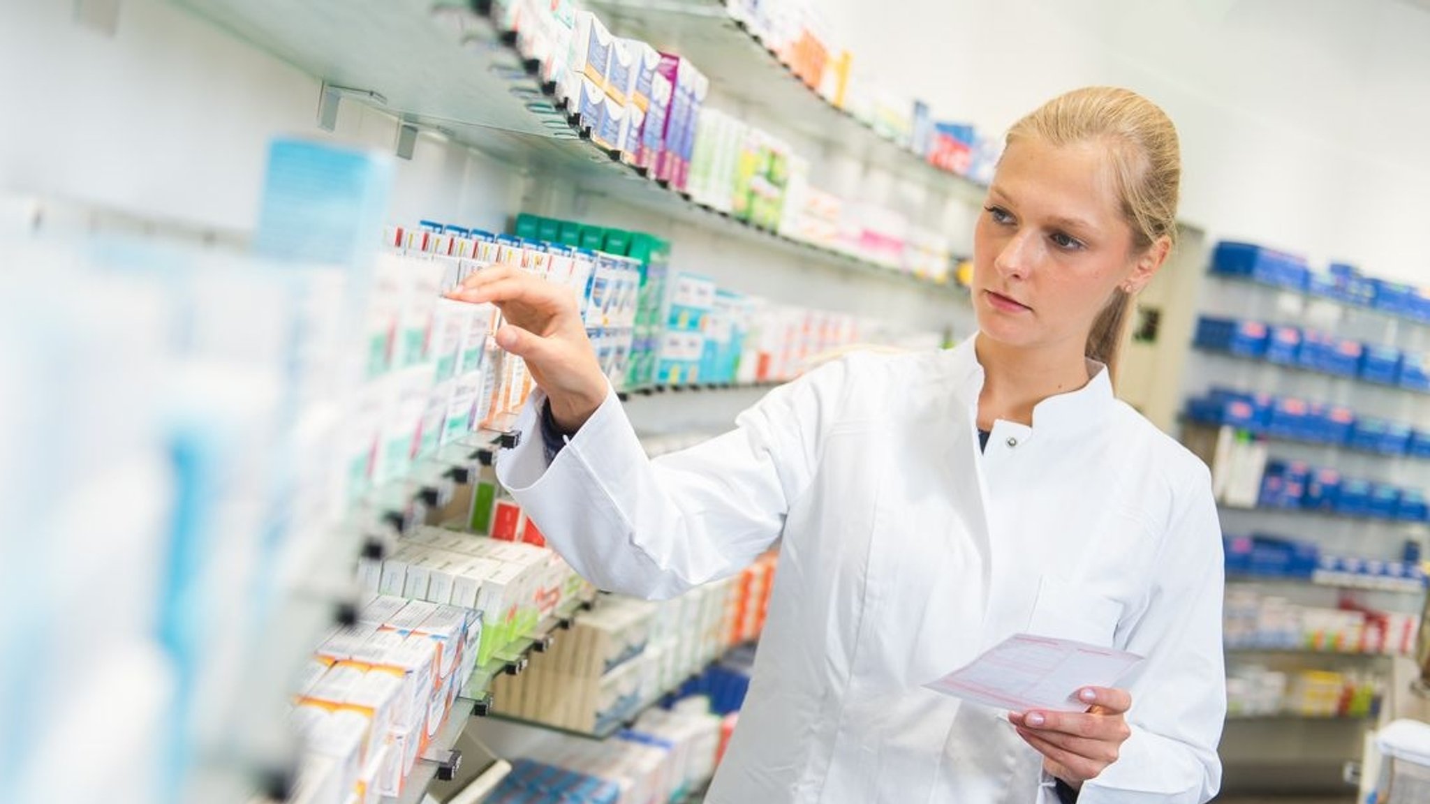 Apothekerin wählt ein auf Papierrezept verschriebenes Medikament aus