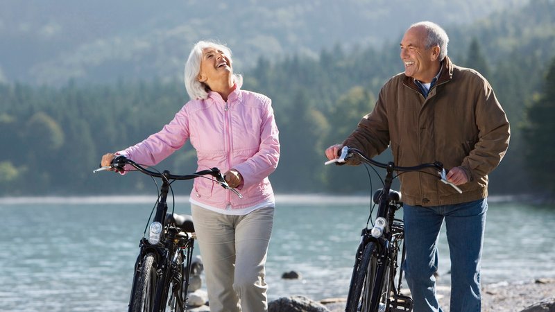 (Symbolbild) Zwei ältere Menschen mit Fahrrädern vor einer See-Kulisse | Bild: picture alliance / Westend61 (Symbolbild) Zwei ältere Menschen mit Fahrrädern vor einer See-Kulisse