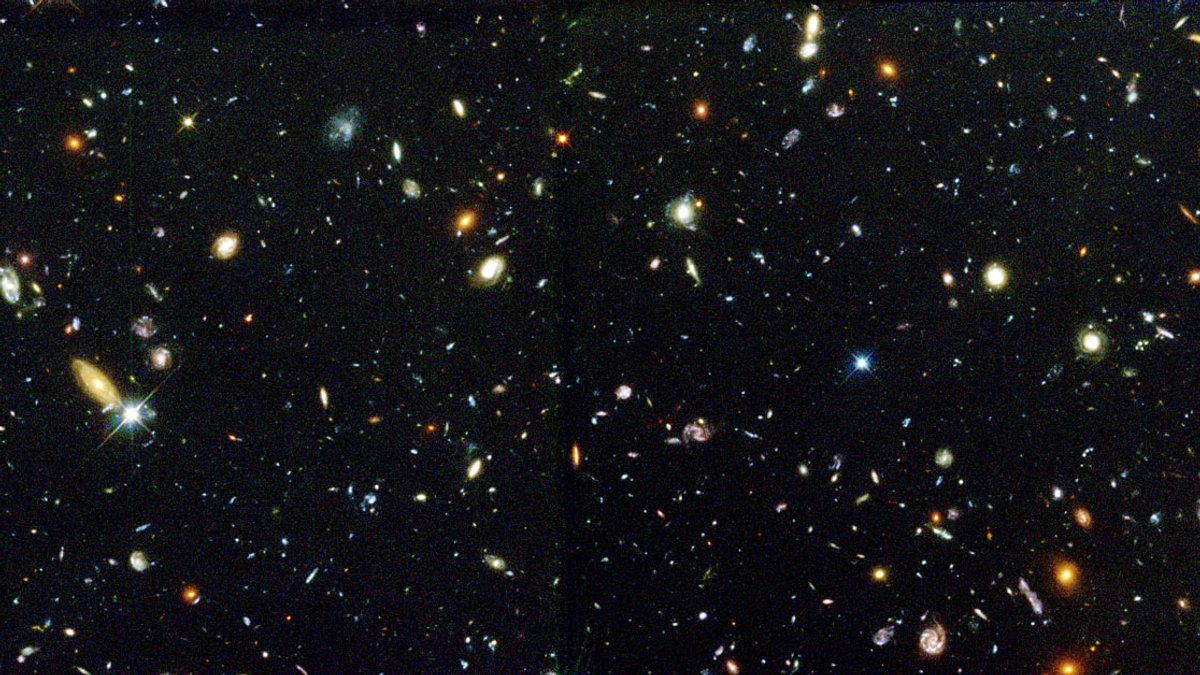 Ausschnitt des Hubble Deep Fields, eine Aufnahme des Hubble-Weltraumteleskops aus den 1990er Jahren. Darauf zu sehen sind zahlreiche bunt leuchtende Galaxien mit unterschiedlichen Formen.
