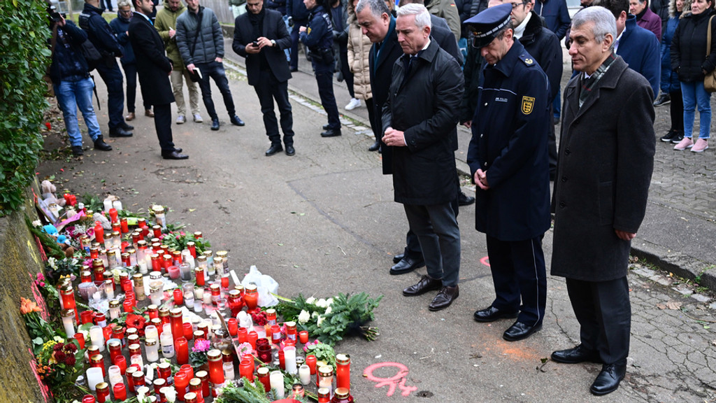 Der baden-württembergische Innenminister steht gemeinsam vor Kerzen und Blumen am Tatort in Illerkirchberg, die an das getötete Mädchen erinnern sollen.