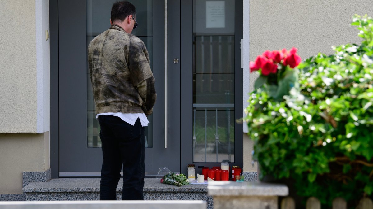 Ein Mann steht vor dem Eingang des Hauses, in dem ein 64-Jähriger drei Menschen erschossen haben soll.
