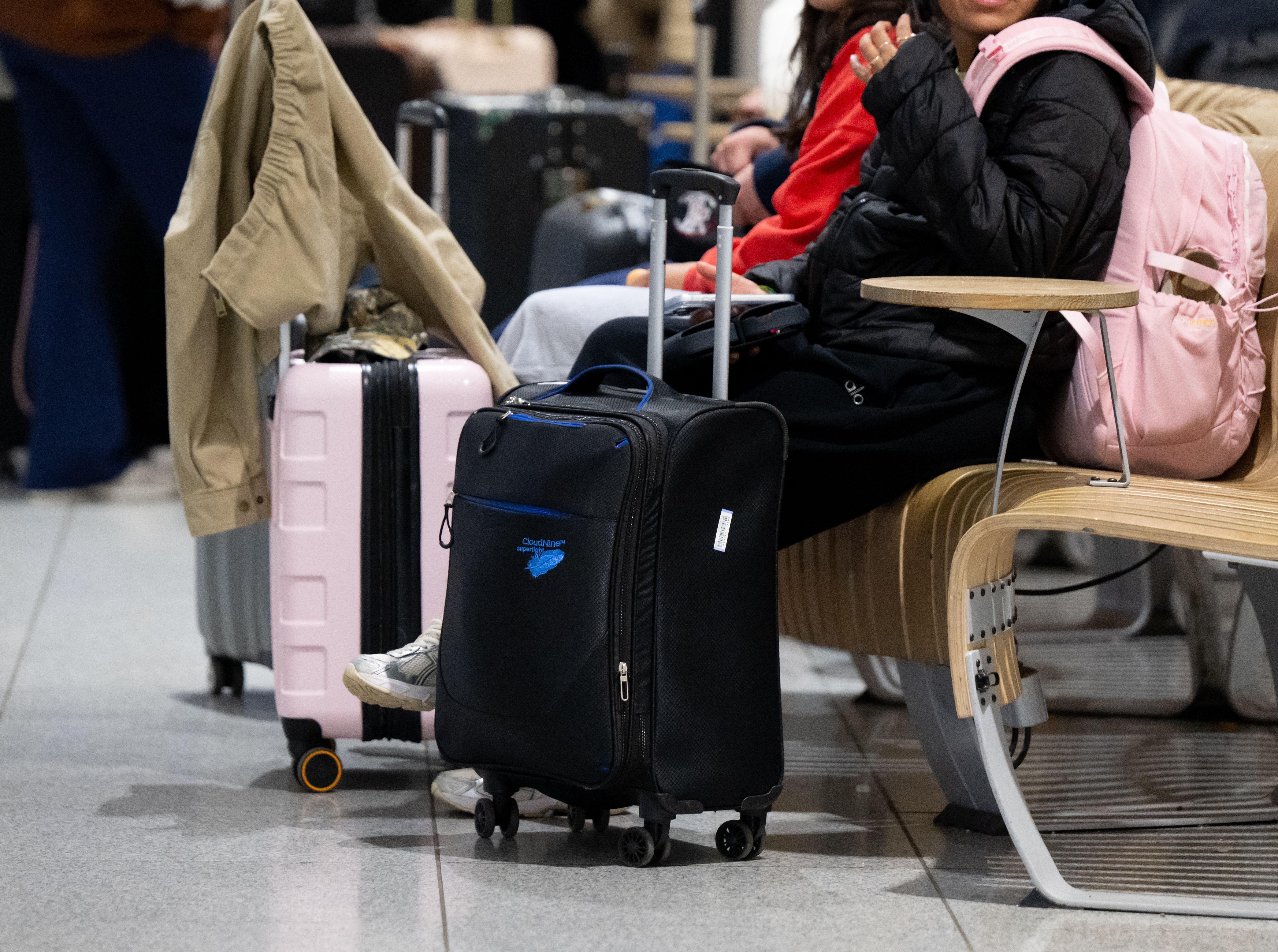  Passagiere stehen am Münchner Flughafen mit ihrem Gepäck an einem Check-In Schalter. 