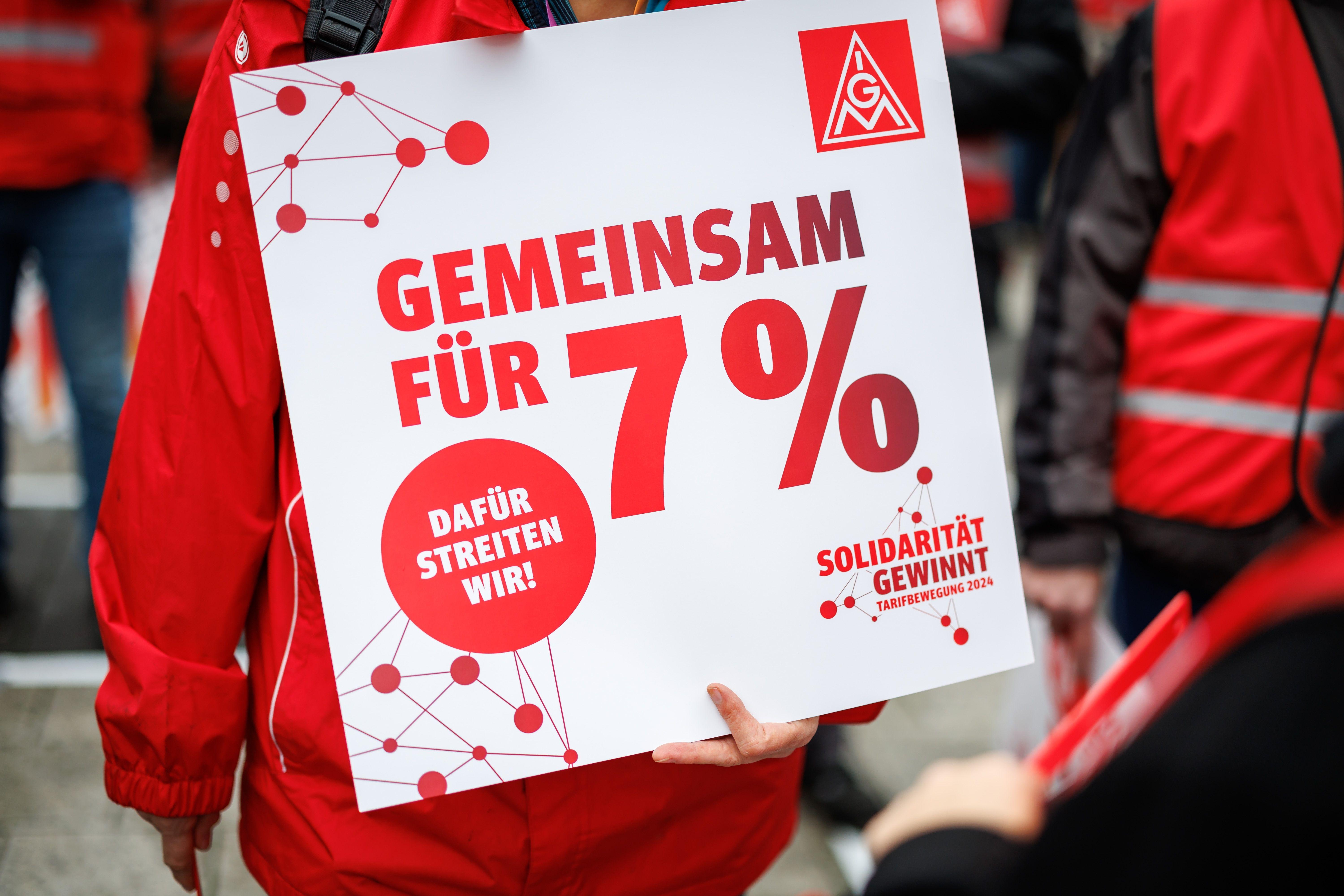 Ein Schild mit der Aufschrift "Gemeinsam für 7 Prozent" ist während einer Kundgebung zu sehen.