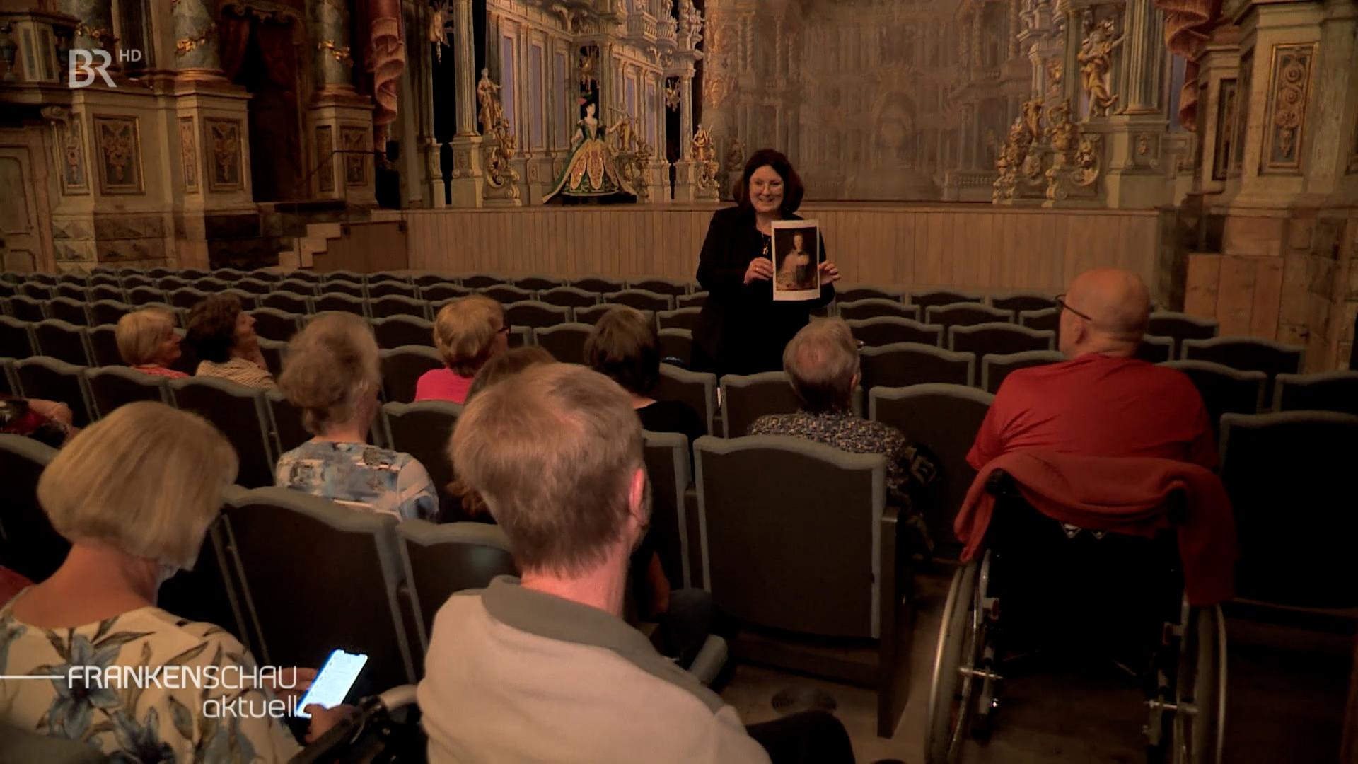Eine Frau hält im Opernhaus ein Foto hoch.