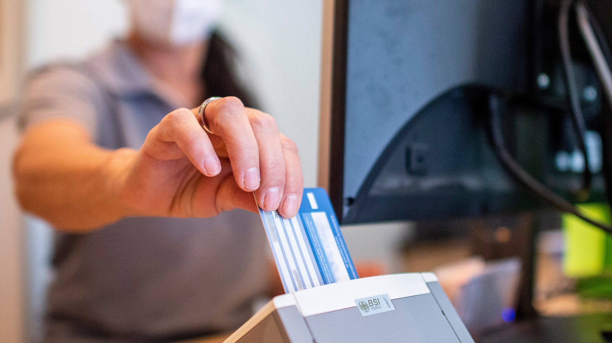 Eine Frau steckt die Gesundheitskarte in den Scanner