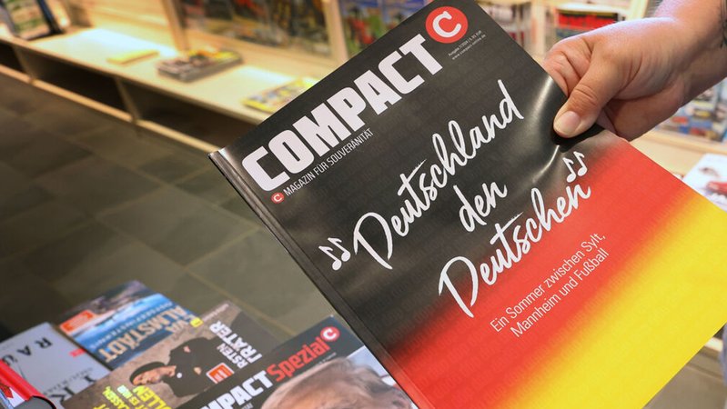Eine Mitarbeiterin einer Bahnhofsbuchhandlung hält eine Ausgabe des Magazins "Compact" hoch | Bild: dpa-Bildfunk/Karl-Josef Hildenbrand Eine Mitarbeiterin einer Bahnhofsbuchhandlung hält eine Ausgabe des Magazins "Compact" hoch