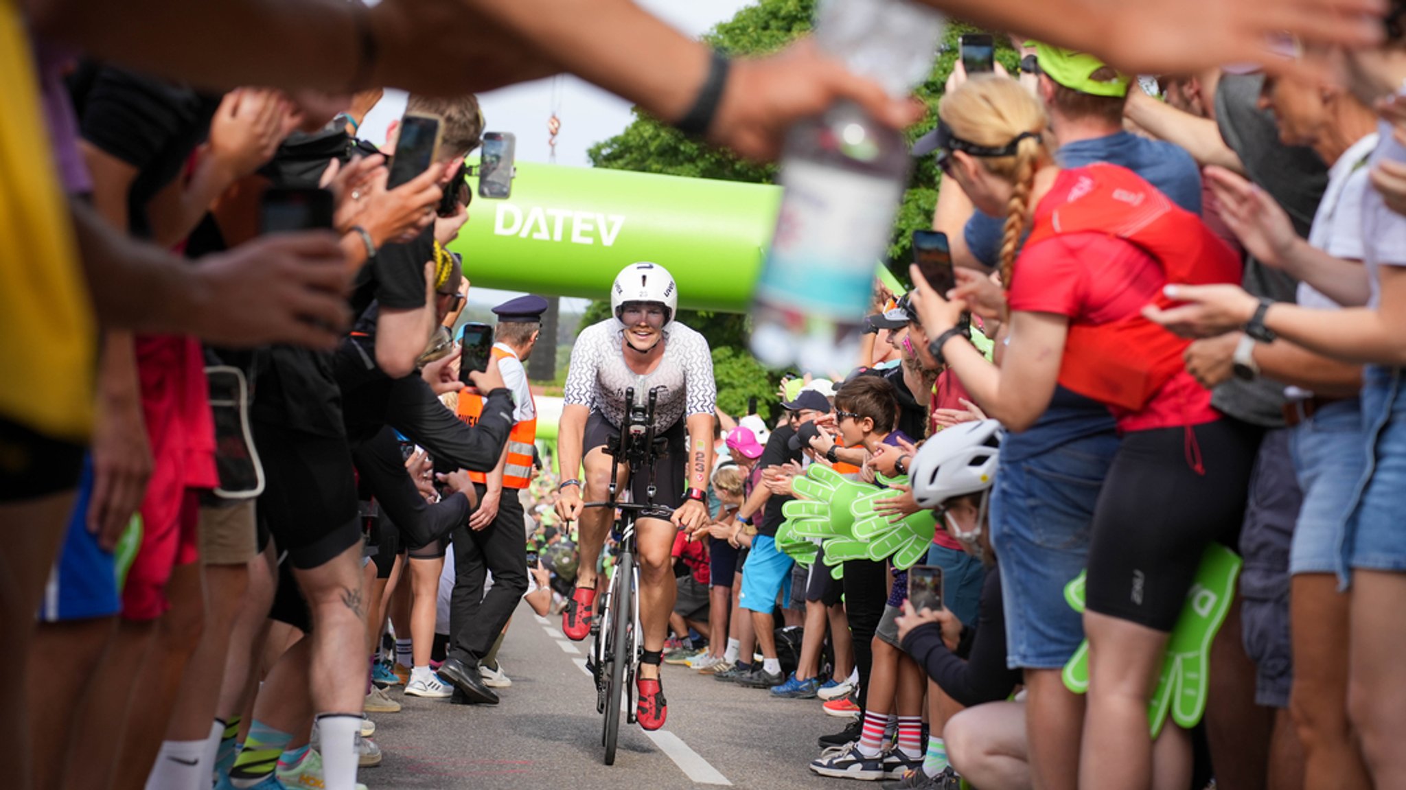 Eine Fahrradfahrerin auf der Strecke beim Challenge Roth. Von rechts und von links halten Menschen Hände in die Strecke. | Bild: BR/Henry Lai Eine Fahrradfahrerin auf der Strecke beim Challenge Roth. Von rechts und von links halten Menschen Hände in die Strecke.