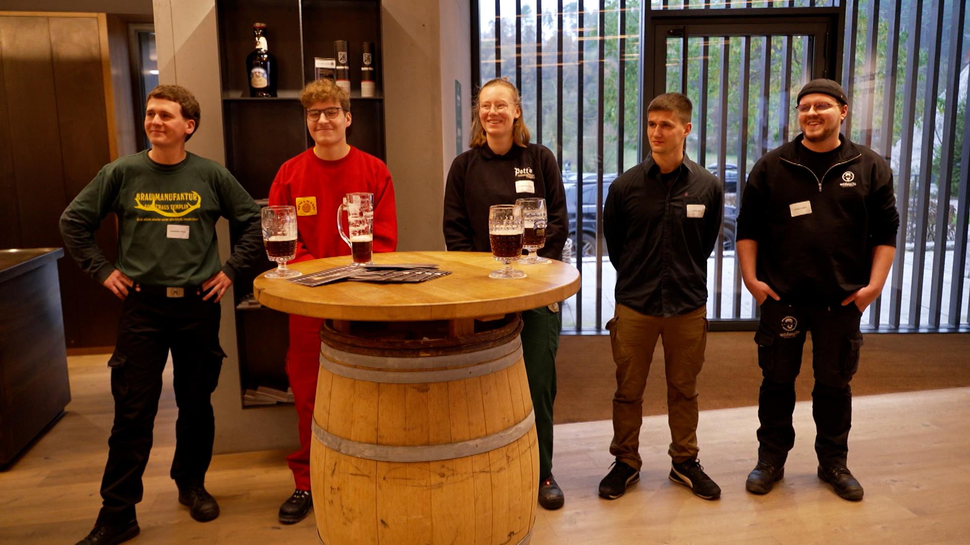 Fünf junge Leute stehen an einem Tisch. 