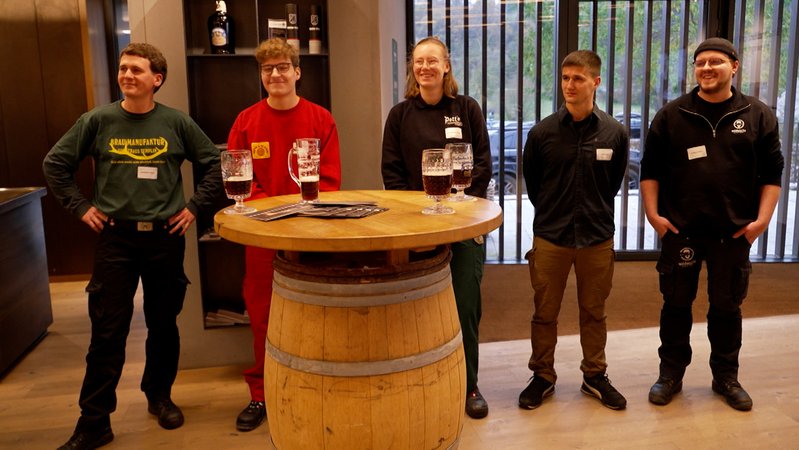 Fünf junge Leute stehen an einem Tisch. | Bild: BR Fünf junge Leute stehen an einem Tisch.