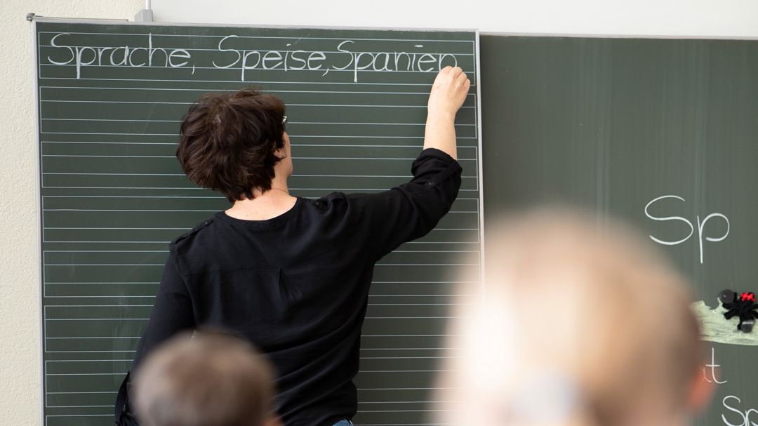 Lehrerin schreibt Wörter an eine Tafel.