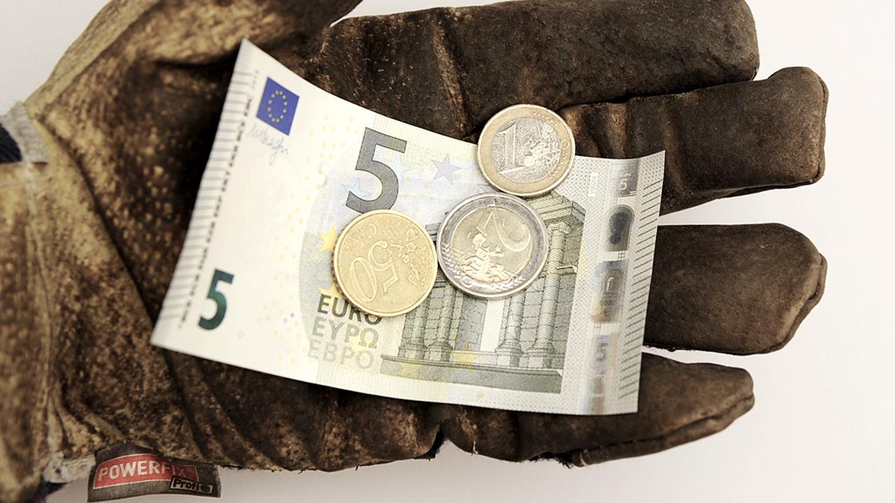Handschuhhand zeigt 8,50 Euro-Mindestlohn, die Regelung soll zunächst nicht für Langzeitarbeitslose gelten