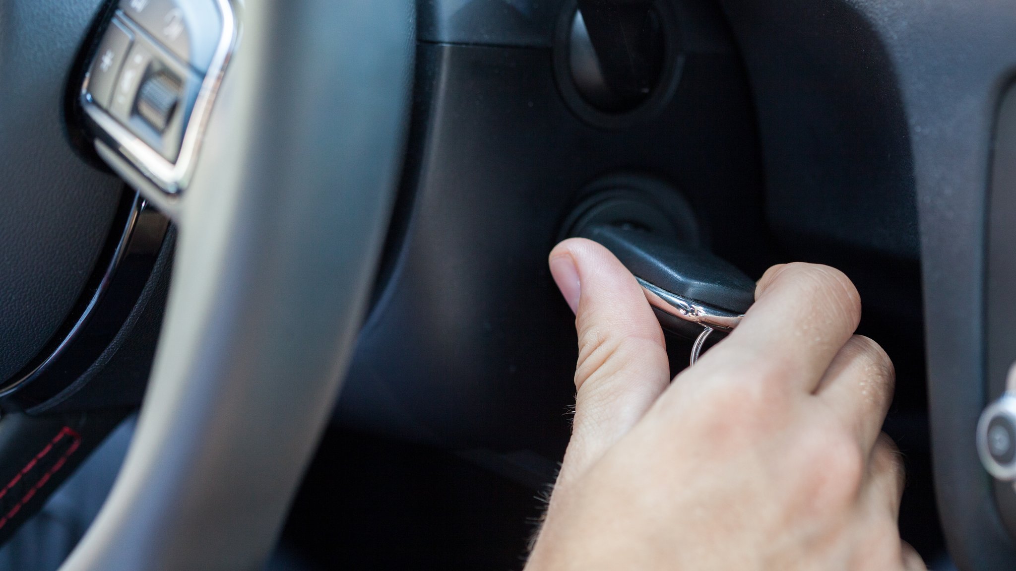 Junge Person startet Auto mit Zündschlüssel.