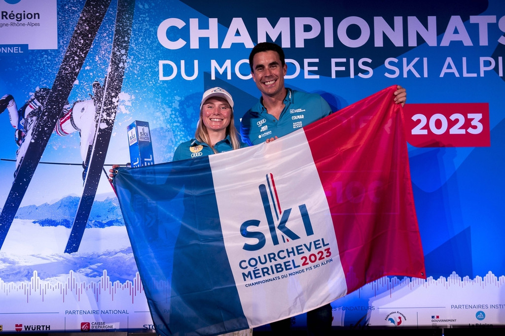 Tessa Worley und Johan Clarey mit Fahne der Alpinen Ski-WM 2023