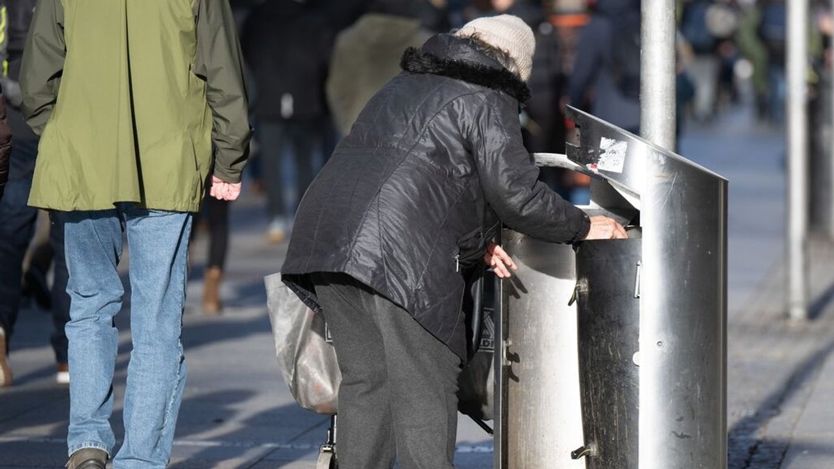ARCHIV - 17.12.2023, Sachsen, Dresden: Eine Frau sucht in einem Mülleimer nach Leergut. (zu dpa: «Unter 1.200 Euro Rente für jeden fünften lange Versicherten») Foto: Sebastian Kahnert/dpa +++ dpa-Bildfunk +++