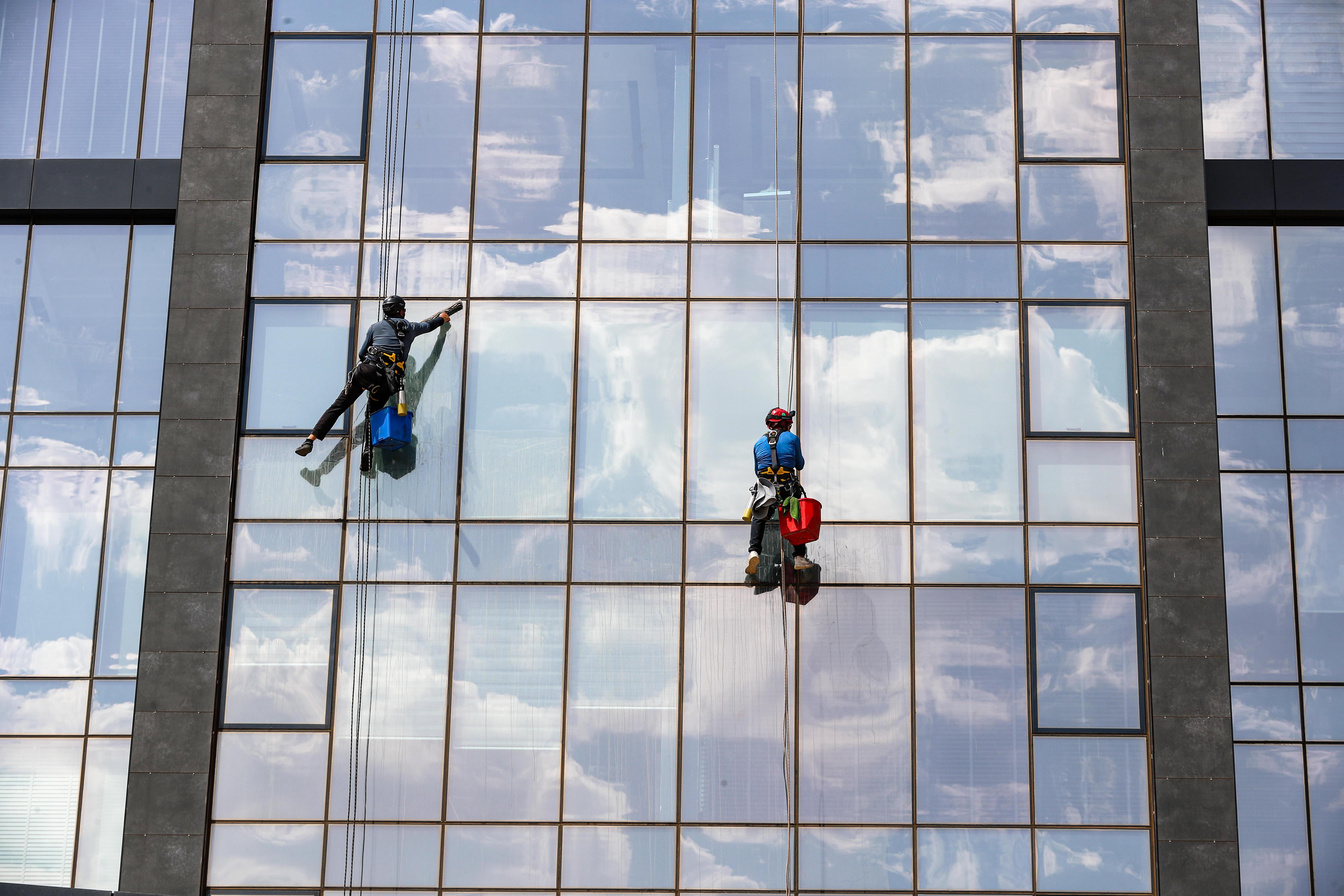 Zwei Fesnterputzer reinigen eine Glasfassade