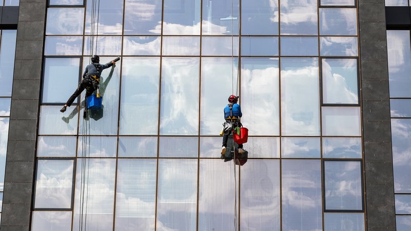 Zwei Fesnterputzer reinigen eine Glasfassade | Bild: picture alliance / Anadolu | Omer Yasin Ergin Zwei Fesnterputzer reinigen eine Glasfassade