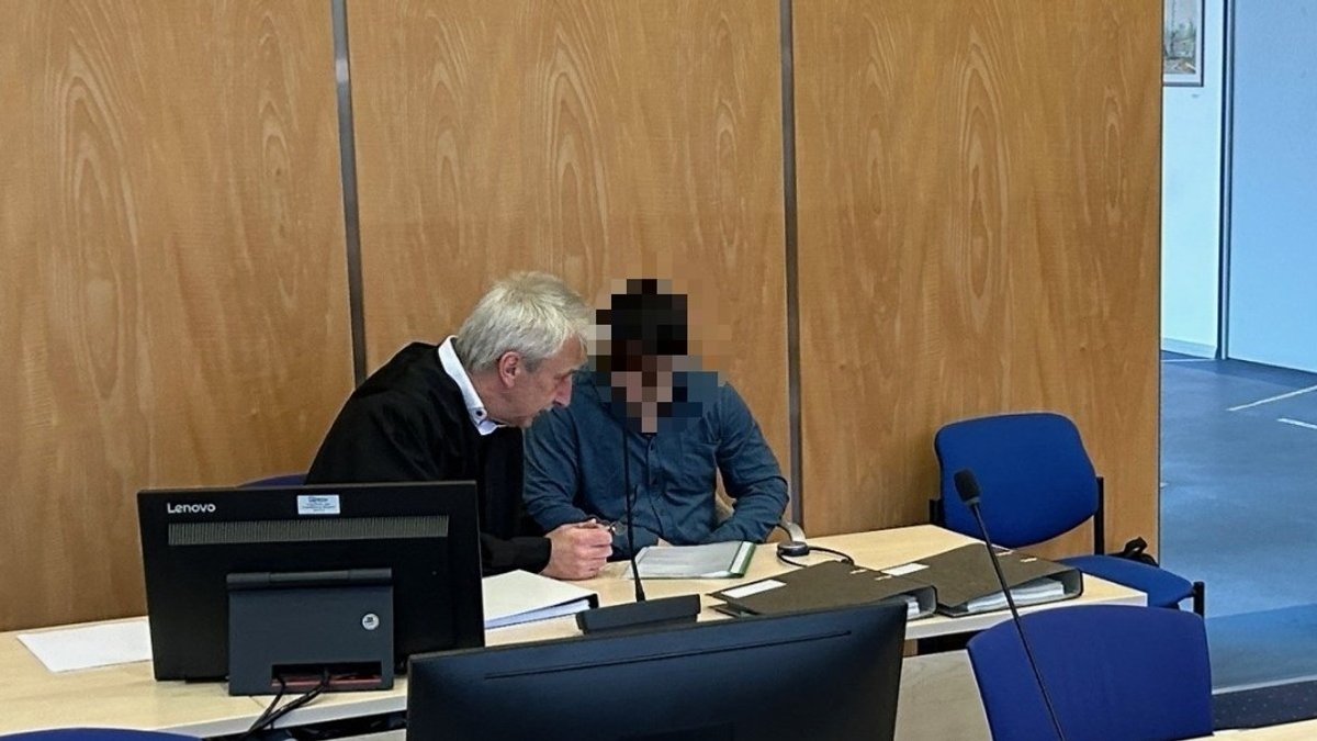 Ein Mann sitzt im Verhandlungssaal neben seinem Anwalt. 