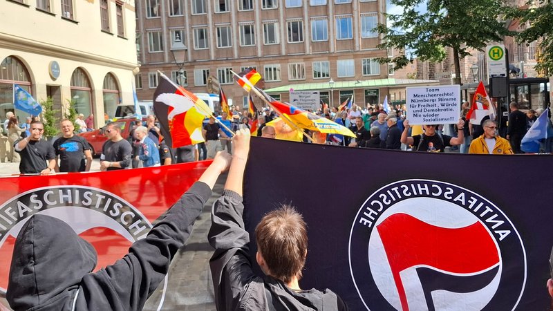 Demonstranten mit Deutschlandfahnen gegenüber Demnstranten mit Antifa-Fahnen. | Bild: BR24/Florian Deglmann Demonstranten mit Deutschlandfahnen gegenüber Demnstranten mit Antifa-Fahnen.