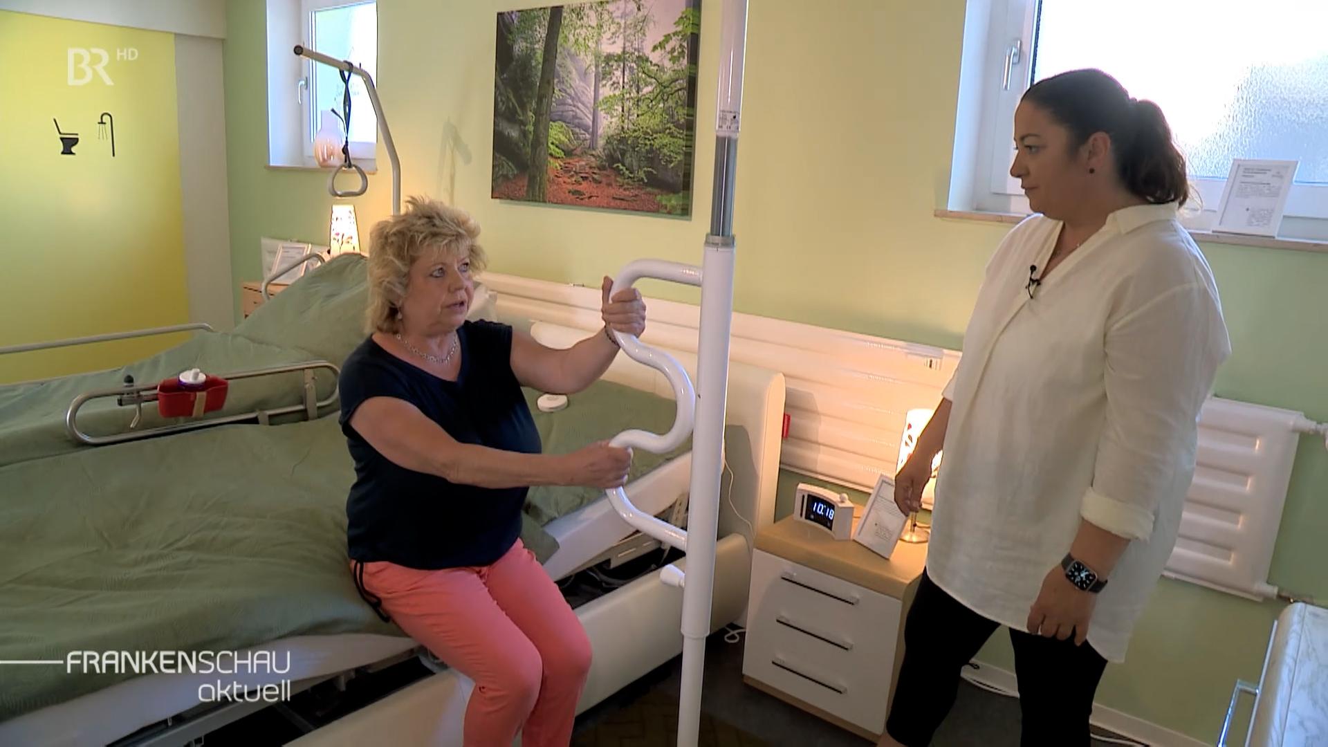 Zwei Frauen testen ein barrierefreies Bett.