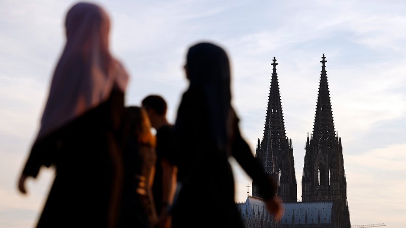 Frauen mit Kopftuch am Kölner Rheinboulevard, im Hintergrund ragt die Doppelspitze des Kölner Doms in den Himmel. | Bild: picture alliance / Panama Pictures | Christoph Hardt Frauen mit Kopftuch am Kölner Rheinboulevard, im Hintergrund ragt die Doppelspitze des Kölner Doms in den Himmel.