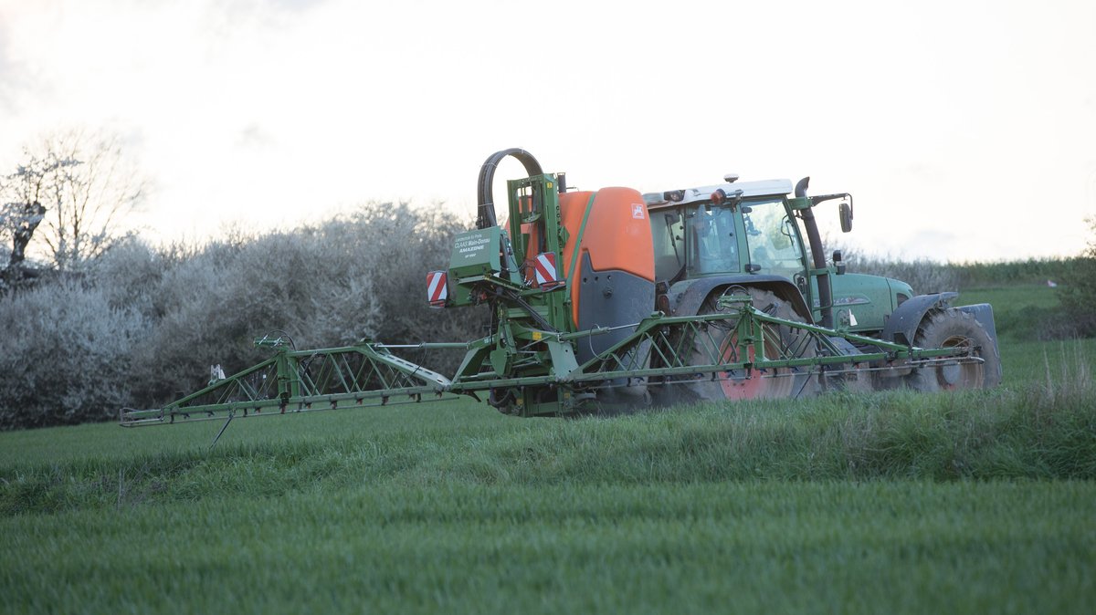 Ein Landwirt bringt mit seinem Traktor und einer großen Pflanzenschutzspritze ein Pflanzenschutzmittel auf das Feld aus (Symbolbild)