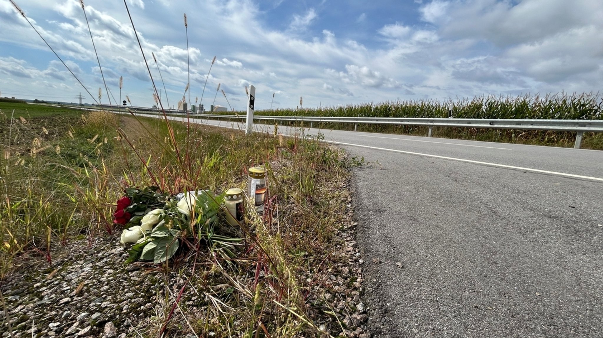 Blumen und Grabkerzen an einer Landstraße