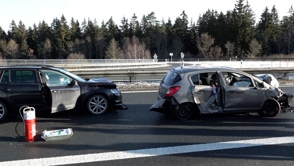 Zwei beschädigte Autos, die aufeinander gefahren sind, stehen auf der Autobahn. 