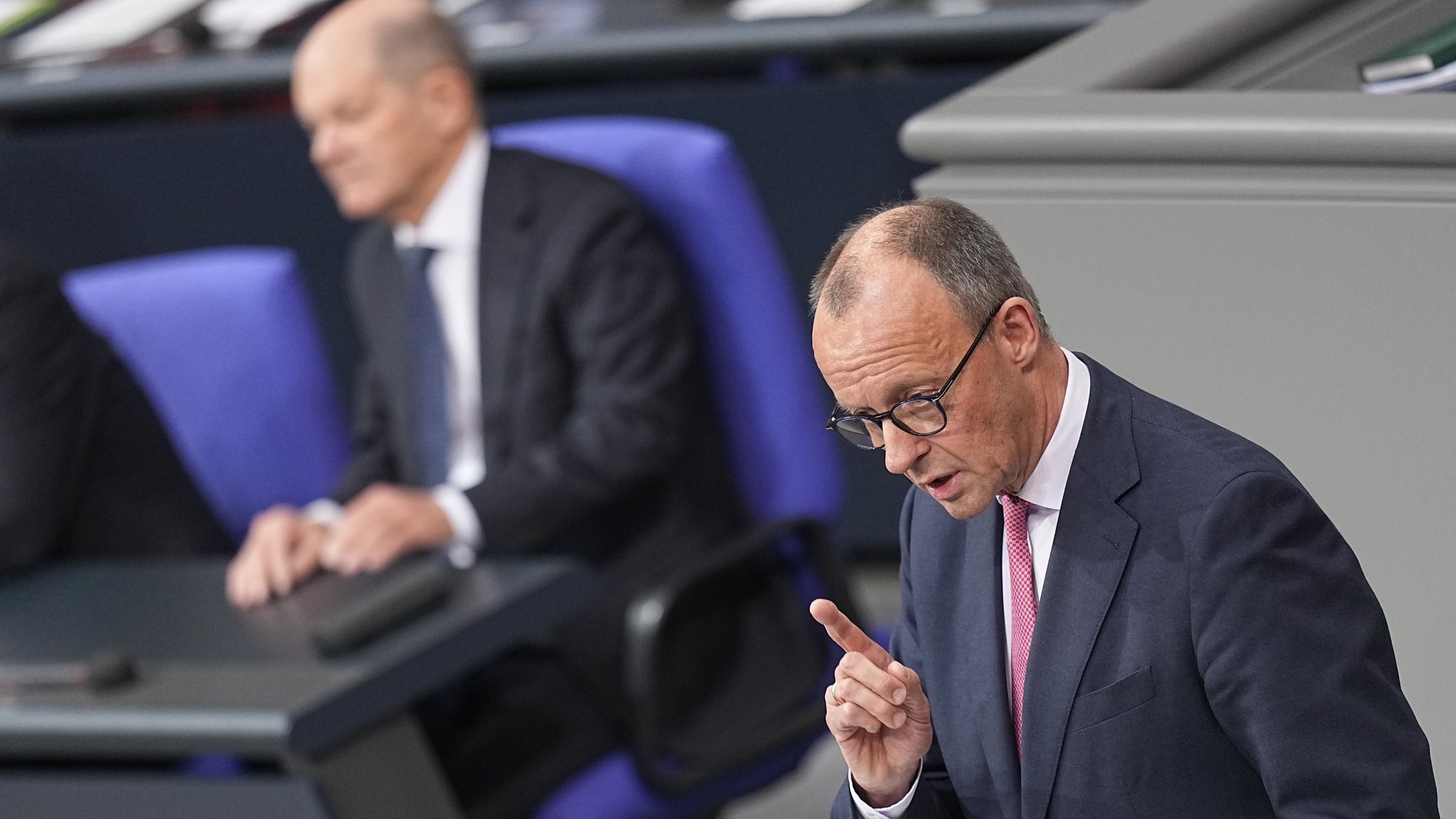 Bundeskanzler Olaf Scholz (SPD) hört Friedrich Merz (r), CDU Bundesvorsitzender und CDU/CSU Fraktionsvorsitzender im Bundestag, zu, als dieser bei der Debatte um das Zustrombegrenzungsgesetz im Plenarsaal im Bundestag spricht.