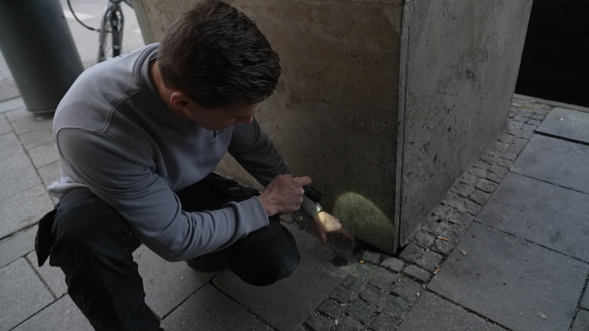 Kammerjäger Jason Puschmann zeigt auf ein Mauseloch im Bereich des Münchner Hauptbahnhofs