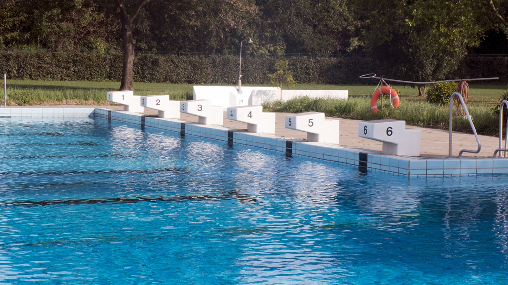 Startblöcke am Beckenrand eines Schwimmbeckens im Freibad. | Bild: stock.adobe.com/Edda Dupree Startblöcke am Beckenrand eines Schwimmbeckens im Freibad.