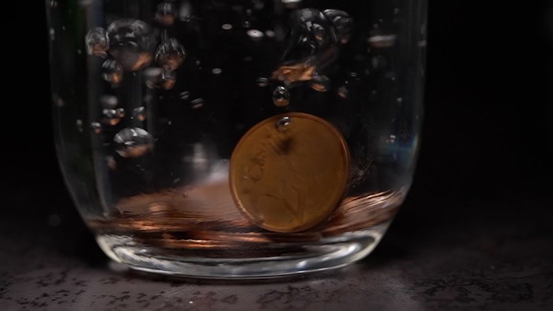 Kupfergeld fällt in Wasserglas.