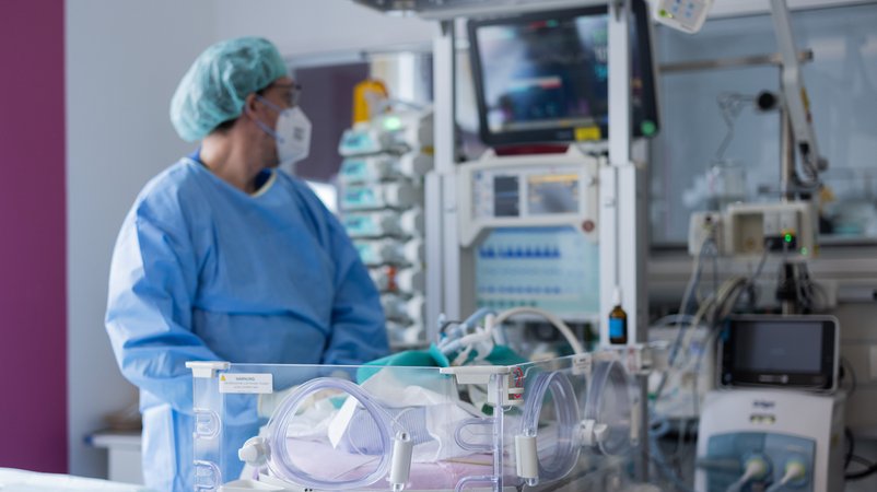Ein Arzt steht in Schutzkleidung und mit Maske in einer Intensivstation und schaut auf einen Monitor. | Bild: picture alliance/dpa | Rolf Vennenbernd Ein Arzt steht in Schutzkleidung und mit Maske in einer Intensivstation und schaut auf einen Monitor.