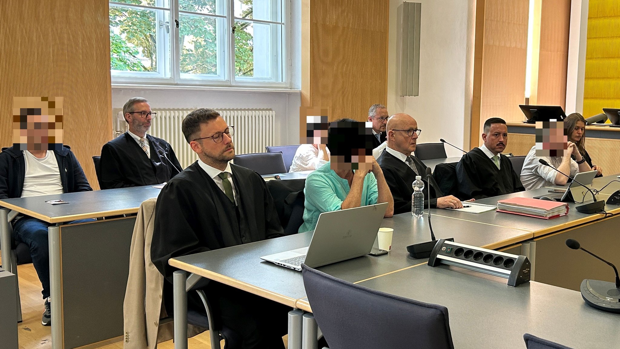 Die vier angeklagten Pflegekräfte mit ihren Rechtsanwälten im Gerichtssaal.