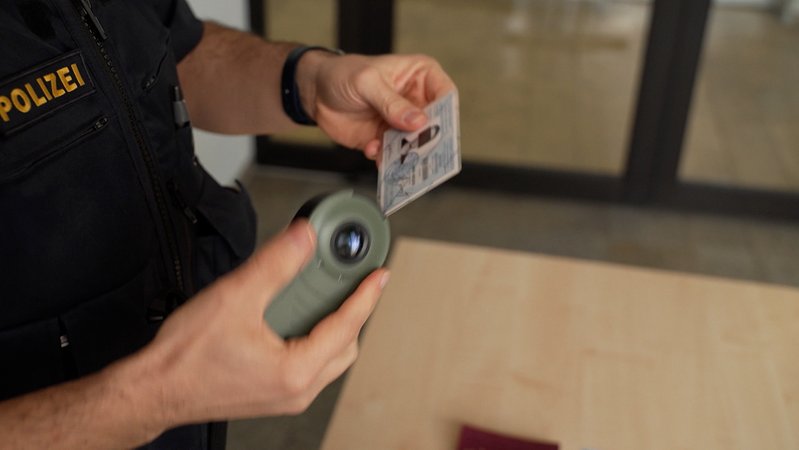 Polizist überprüft ein Ausweisdokument. | Bild: Bayerischer Rundfunk 2024 Polizist überprüft ein Ausweisdokument.
