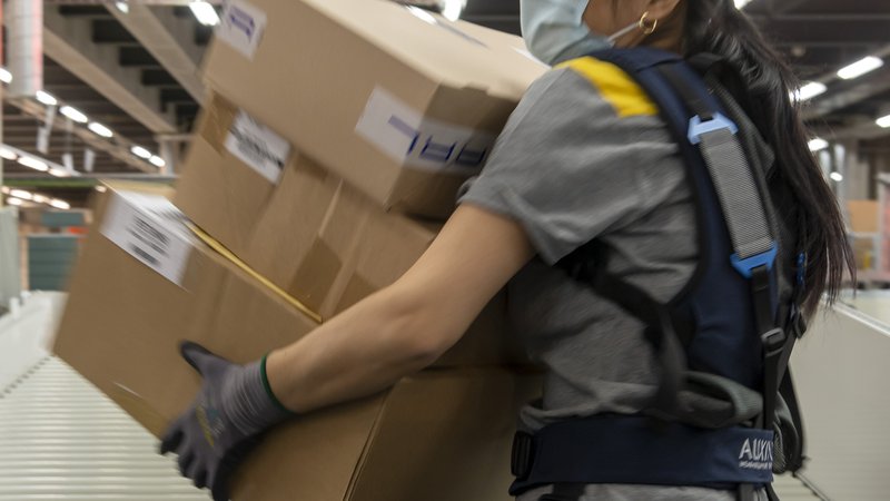 Eine Angestellte trägt ein Exoskelett bei der Sortierung der Pakete im regionalen Paketzentrum der Post in Basel