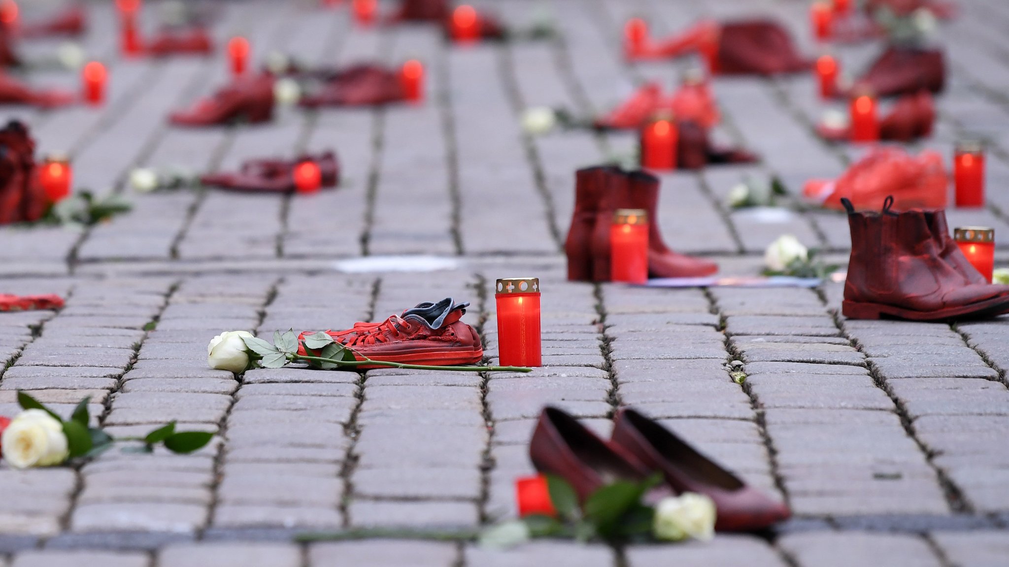 25.11.2021 Internationalen Tag gegen Gewalt an Frauen: Schuh-Aktion zum Thema Femizide in Deutschland auf dem Tübinger Marktplatz, Rote Schuhe mit Grablichtern und weißen Rosen