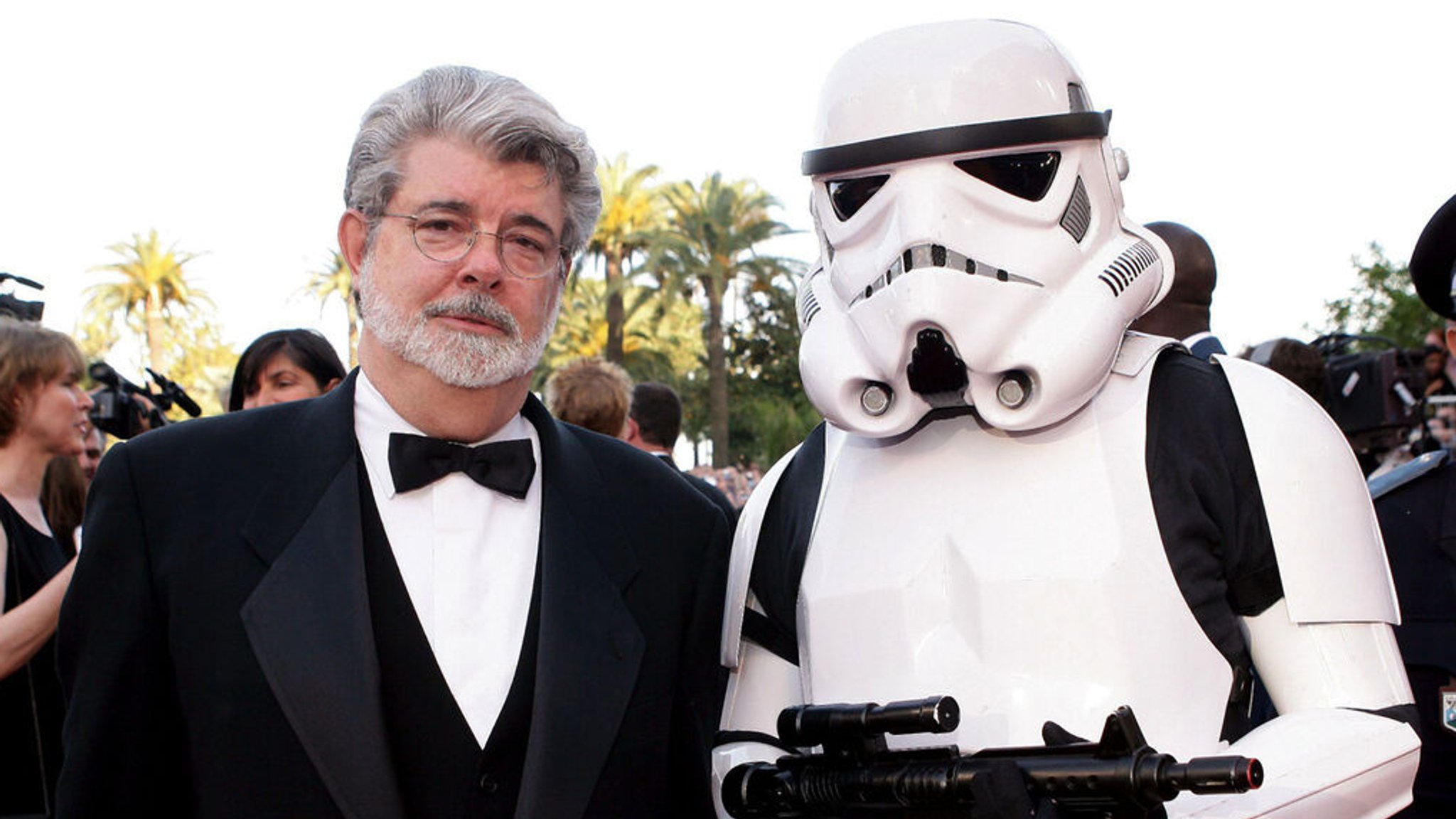ARCHIV - 15.05.2005, Frankreich, Cannes: Der US-Regisseur George Lucas (l) steht auf dem roten Teppich mit einem «Star Wars Stormtrooper» beim 58. Filmfestival von Cannes vor der Filmvorführung von «Star Wars: Episode III - Die Rache der Sith». Es war das letzte Mal, dass er für «Star Wars» hinter der Kamera stand und sich das Drehbuch ausdachte. Zum 20. Jubiläum kommt «Star Wars: Episode III - Die Rache der Sith» für kurze Zeit wieder in die Kinos. (zu dpa: «Zum Jubiläum im Kino: Als «Star Wars» die Unschuld verlor») Foto: epa Sipa Niviere/SIPA/dpa +++ dpa-Bildfunk +++
