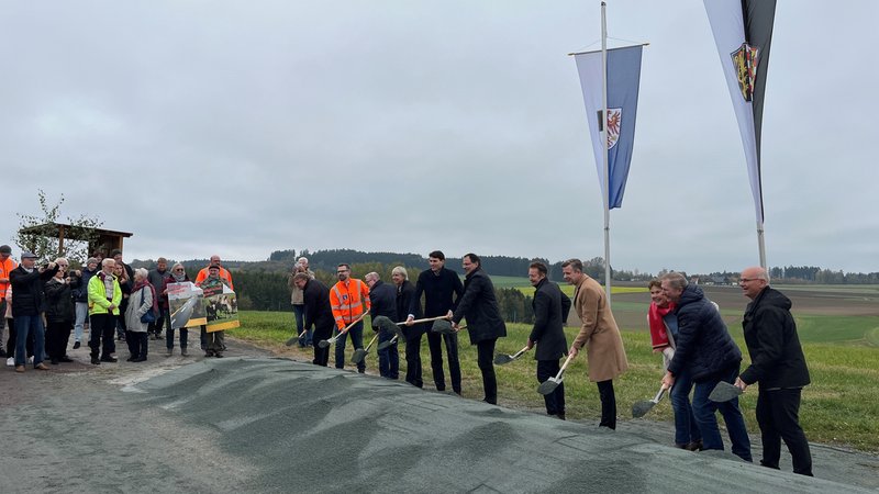Mehrere Menschen vollziehen einen Spatenstich. Zuseher begutachten die Szene. Zwei von ihnen halten Plakate in den Händen. | Bild: BR/Annerose Zuber Mehrere Menschen vollziehen einen Spatenstich. Zuseher begutachten die Szene. Zwei von ihnen halten Plakate in den Händen.