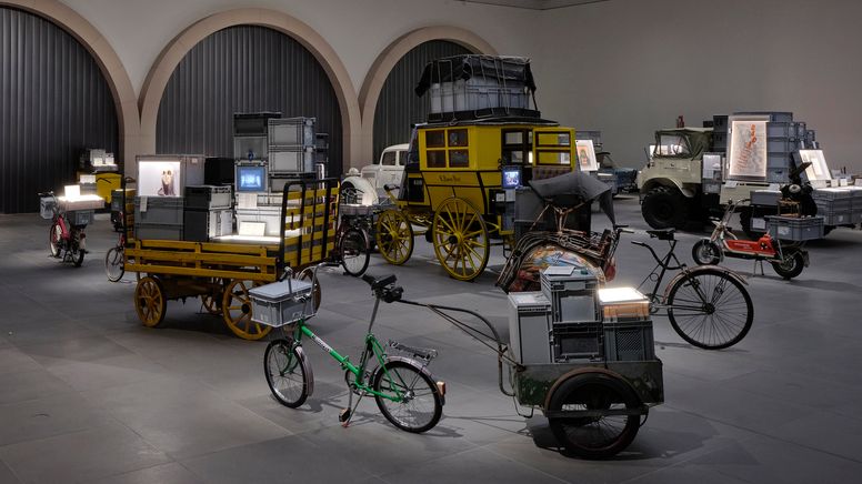 Alte Fahrzeuge, beladen mit Archivboxen in einem Saal | Bild:Annette Kradisch