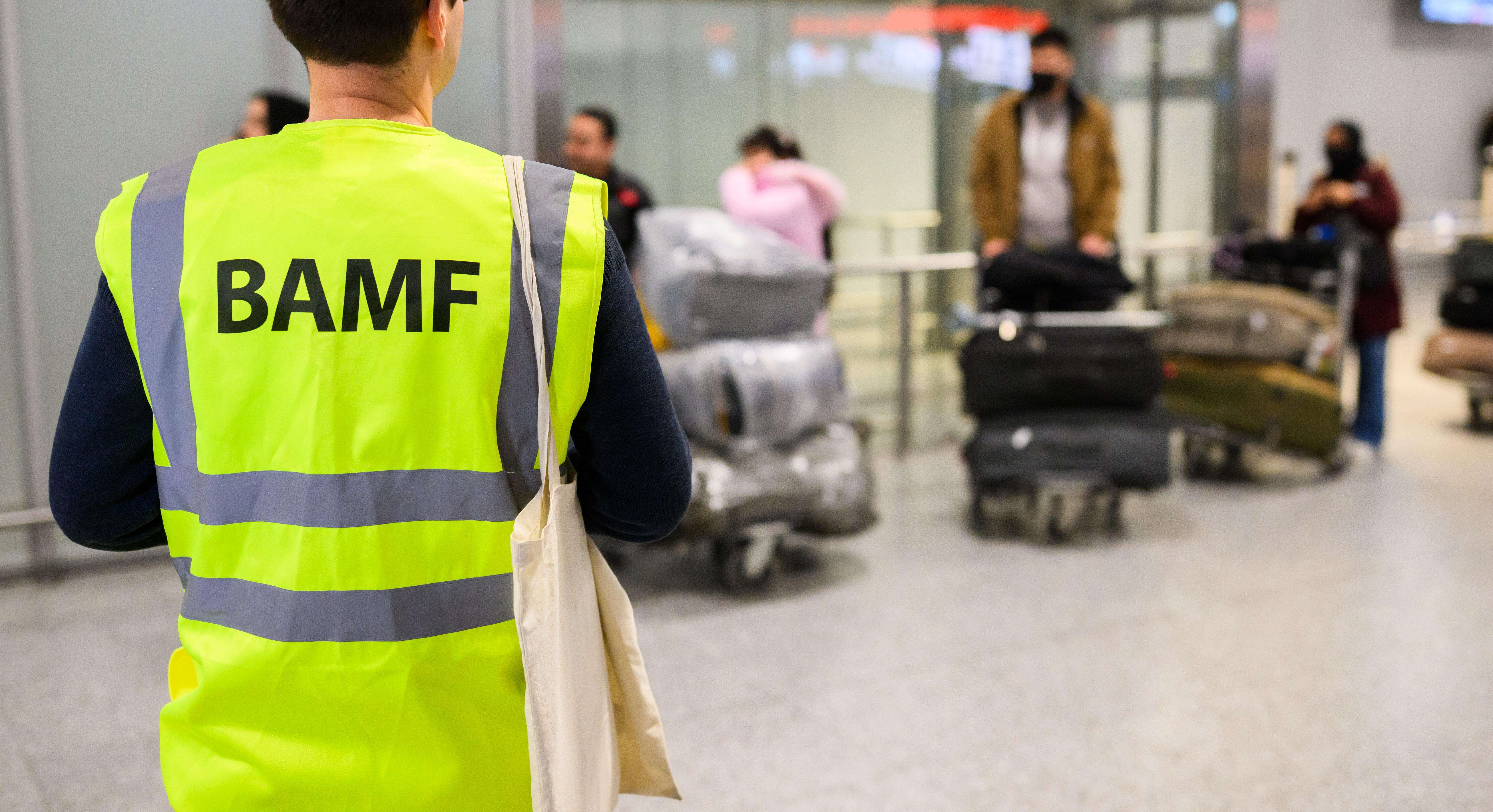 ARCHIV (20.11.2025): Ein Mitarbeiter vom BAMF Bundesamt für Migration und Flüchtlinge steht im Flughafen Hannover vor Afghaninnen und Afghanen aus den Bundesaufnahmeprogrammen. Zum sechsten Mal seit dem Regierungswechsel sind in der pakistanischen Hauptstadt Islamabad Afghanen mit Aufnahmezusage Richtung Deutschland geflogen.