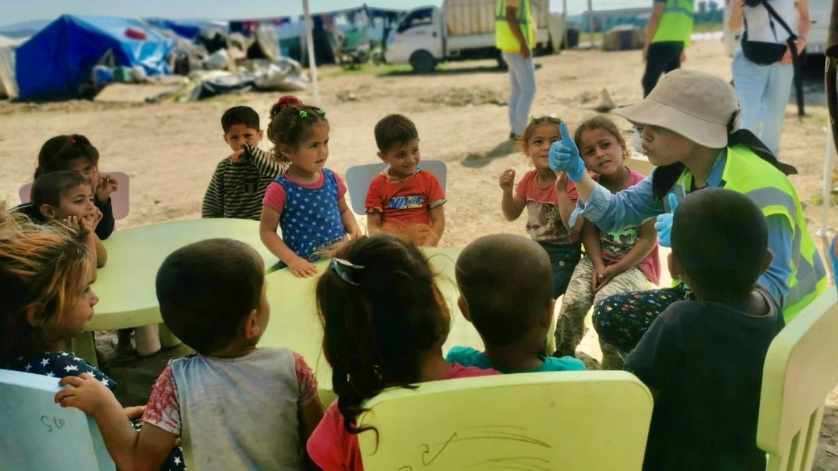 Eine Gruppe von Kindern, die zusammen an Tischen im Freien sitzt