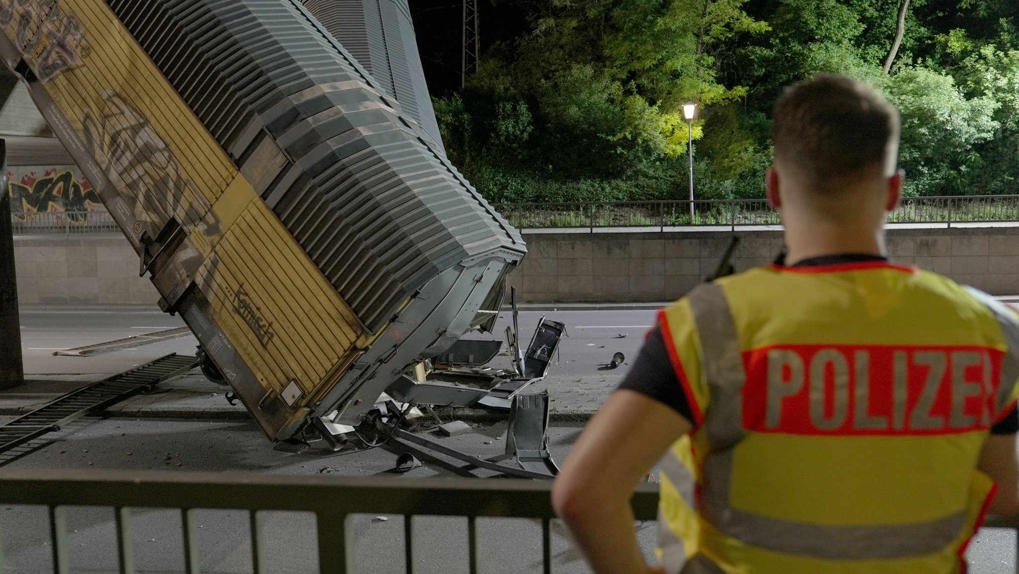 Zwei Waggons eines Güterzugs liegen auf einer Straße, nachdem sie von einer Brücke gestürzt sind. | Bild: dpa-Bildfunk/Ehsan Monajati Zwei Waggons eines Güterzugs liegen auf einer Straße, nachdem sie von einer Brücke gestürzt sind.