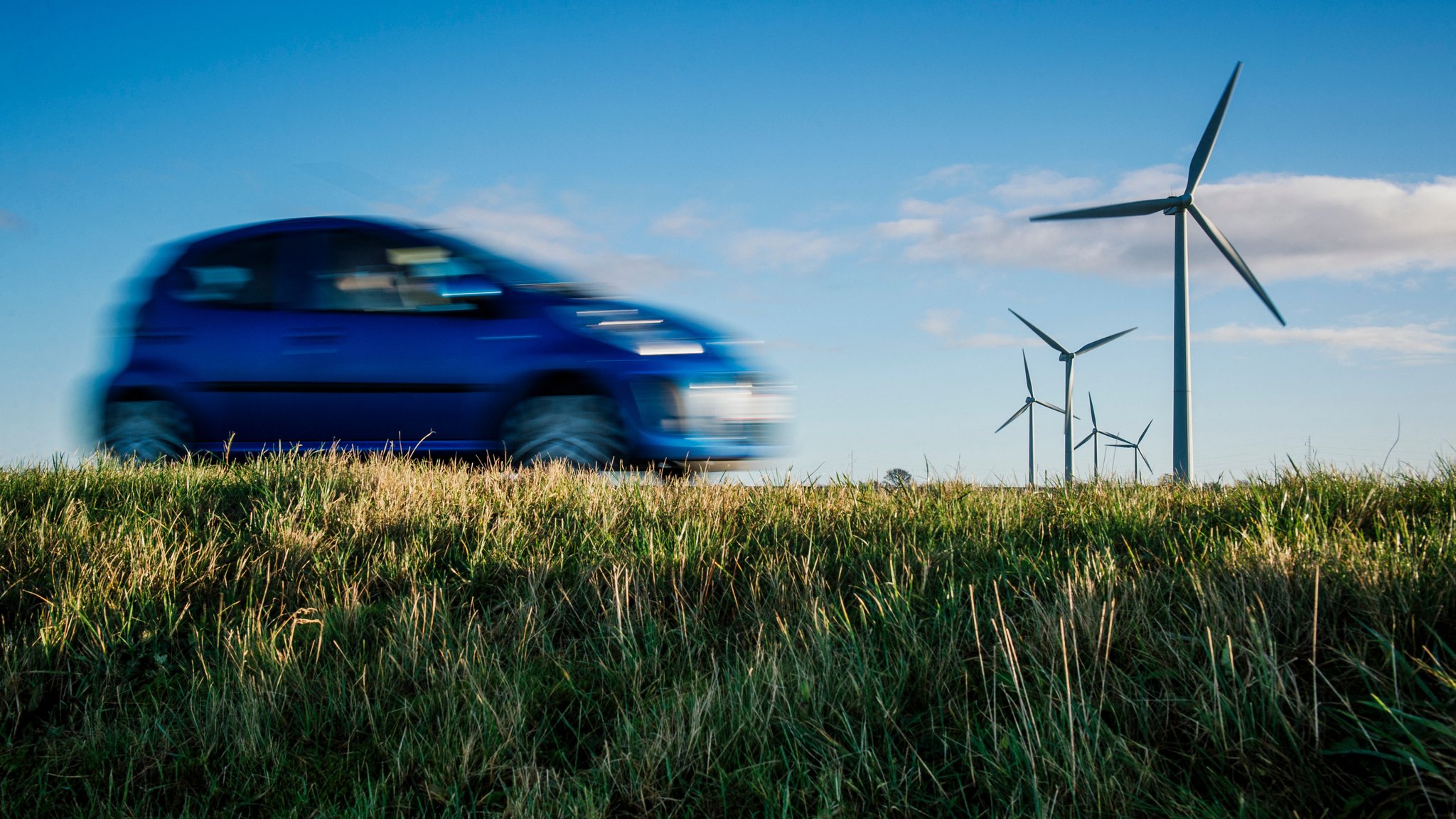 Ein Auto fährt an einigen Windrädern vorbei