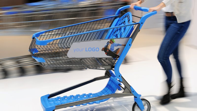Eine Frau schiebt einen blauen Einkaufswagen aus Kunststoff.