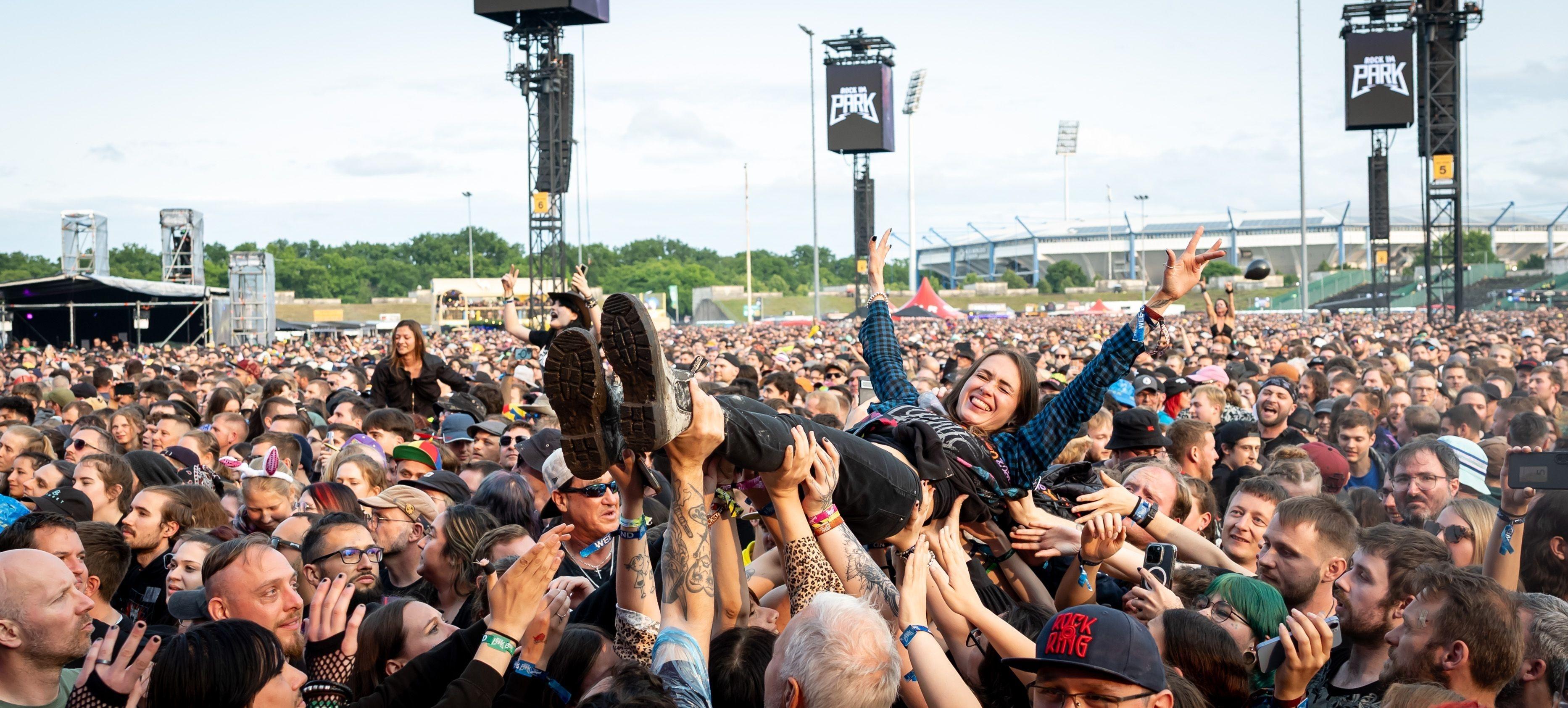 Eine Zuschauerin wird beim Open-Air-Festival "Rock im Park" 2025 während eines Konzerts beim Crowd-Surfing auf Händen getragen. 