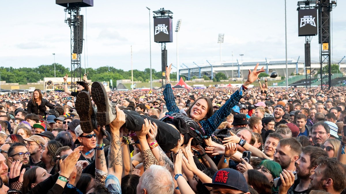 Eine Zuschauerin wird beim Open-Air-Festival "Rock im Park" 2025 während eines Konzerts beim Crowd-Surfing auf Händen getragen. 