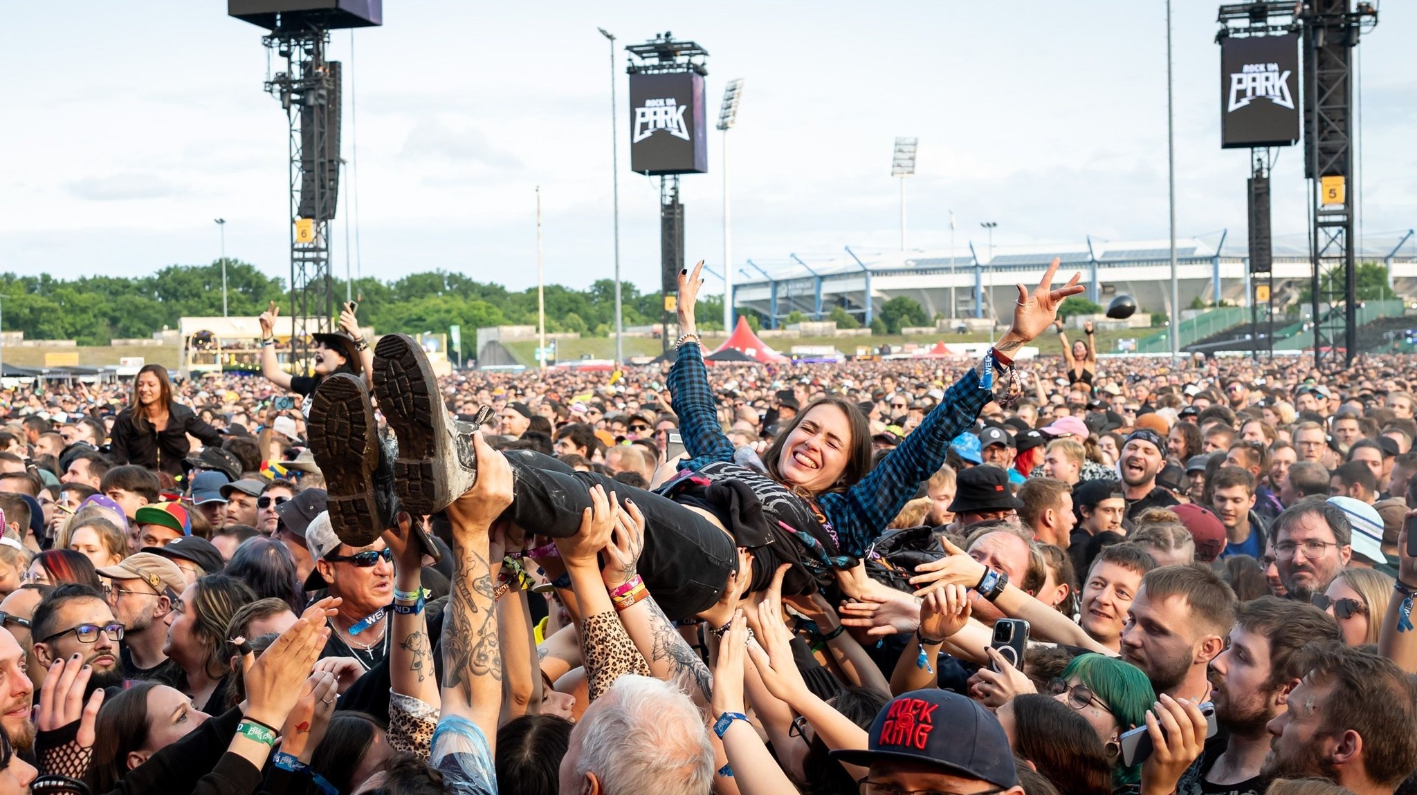 Eine Zuschauerin wird beim Open-Air-Festival "Rock im Park" 2025 während eines Konzerts beim Crowd-Surfing auf Händen getragen. 