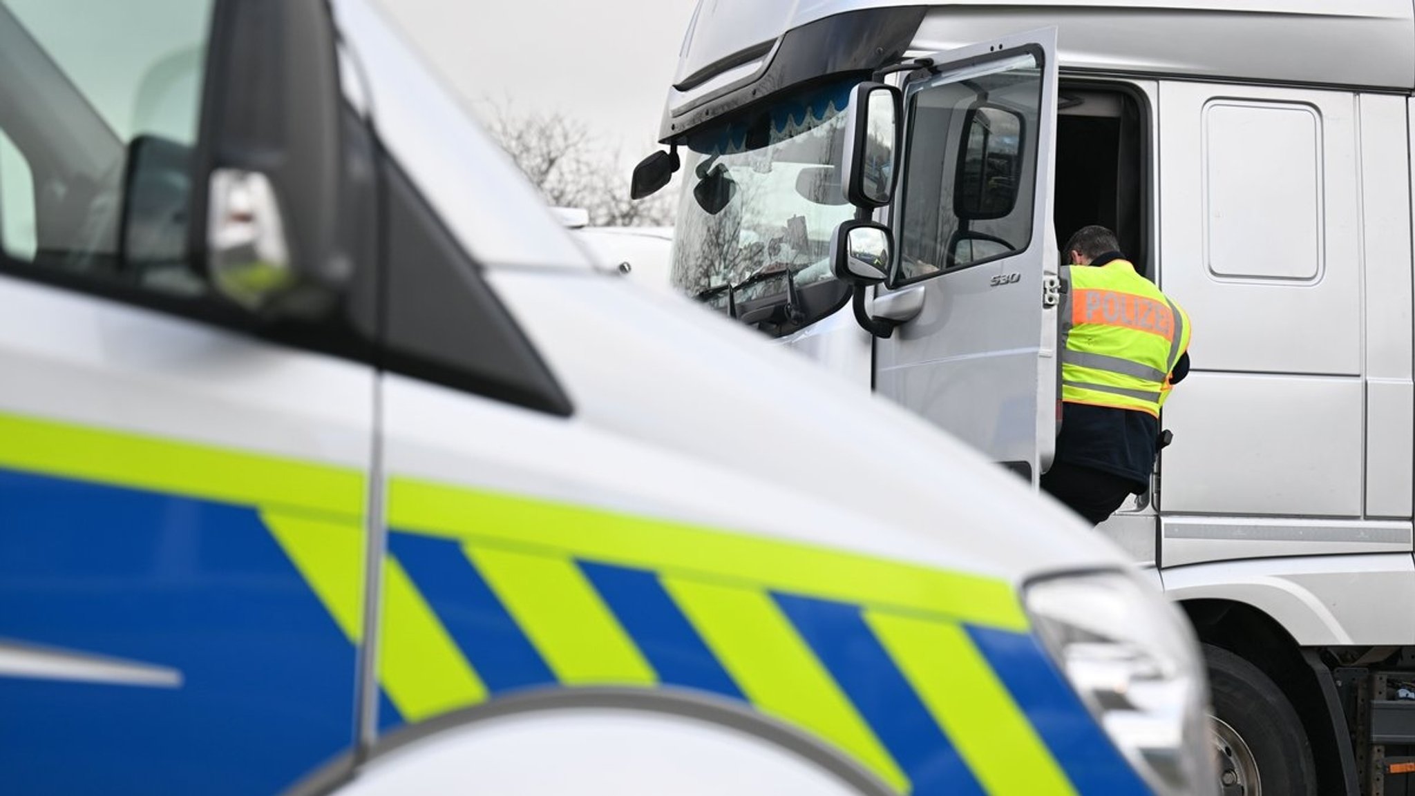 Symbolbild: Ein Polizist kontrolliert auf dem Parkplatz einen LKW. 